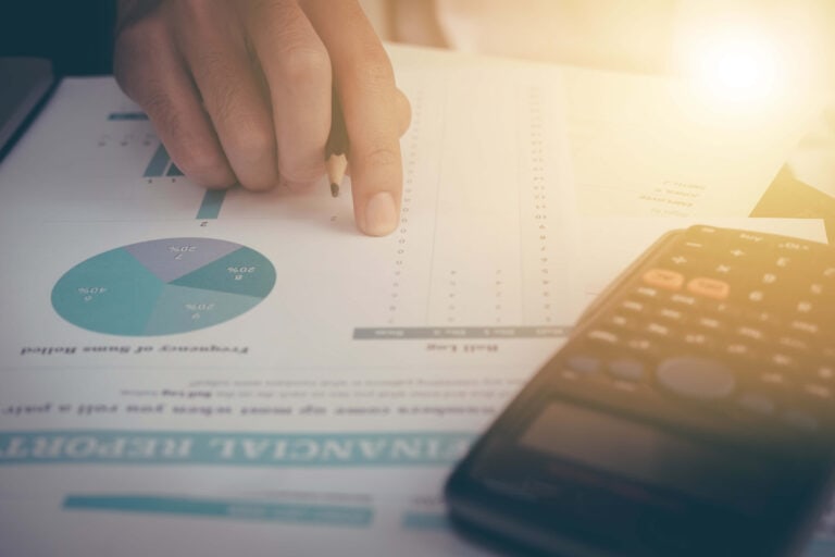 Regnskapsdata og grafer på papir med kalkulator og penn, økonomi- og finansanalyse.