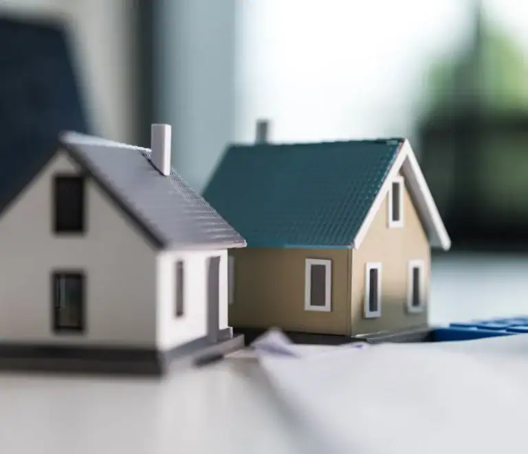 Modell av moderne husmodell med detaljerte takflater og vinduer, på en bordplate, brukt til arkitektonisk planlegging og bygningsdesign.